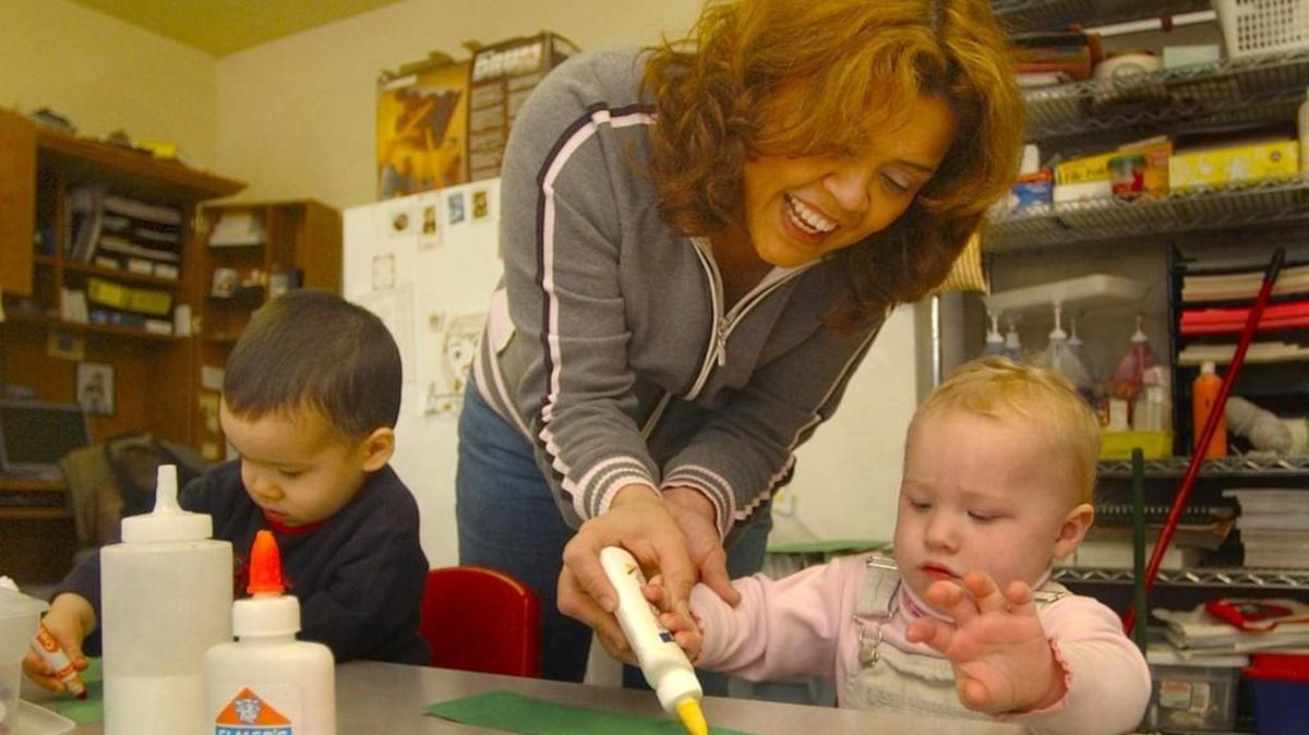 In a 2014 file photo, Maggie Stewart helps little ones at The Children’s House daycare apply the required amount of glue for a holiday project at The Children's House daycare.