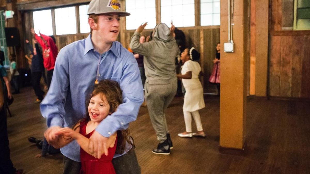 In this Saturday, Jan. 16, 2016 photo, big brother Tyrus Gilbertson whisks around sister Corrine, 6, as they dance to tunes from the Michael Benson Band during a special event donated to people staying at Mary's Place shelter at Sodo Park in Seattle.