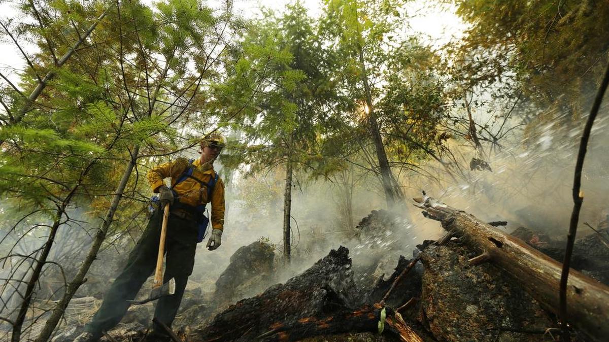 
Washington National Guard Sgt. Matt Eagen, left, breaks up wood and soil looking for hot spots as the hillside is sprayed with water, Tuesday, Aug. 18, 2015, near Chelan, Wash. The troops in Washington state were part of a massive response to blazes burning uncontrolled throughout the West. 
