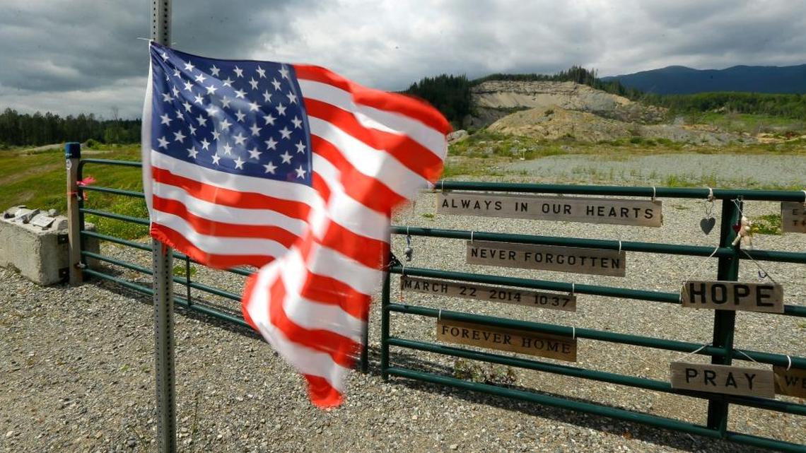 In this Wednesday, May 25, 2016 photo, a U.S. flag flutters in the wind near the site of a massive 2014 mudslide that killed 43 people in Oso, Wash.