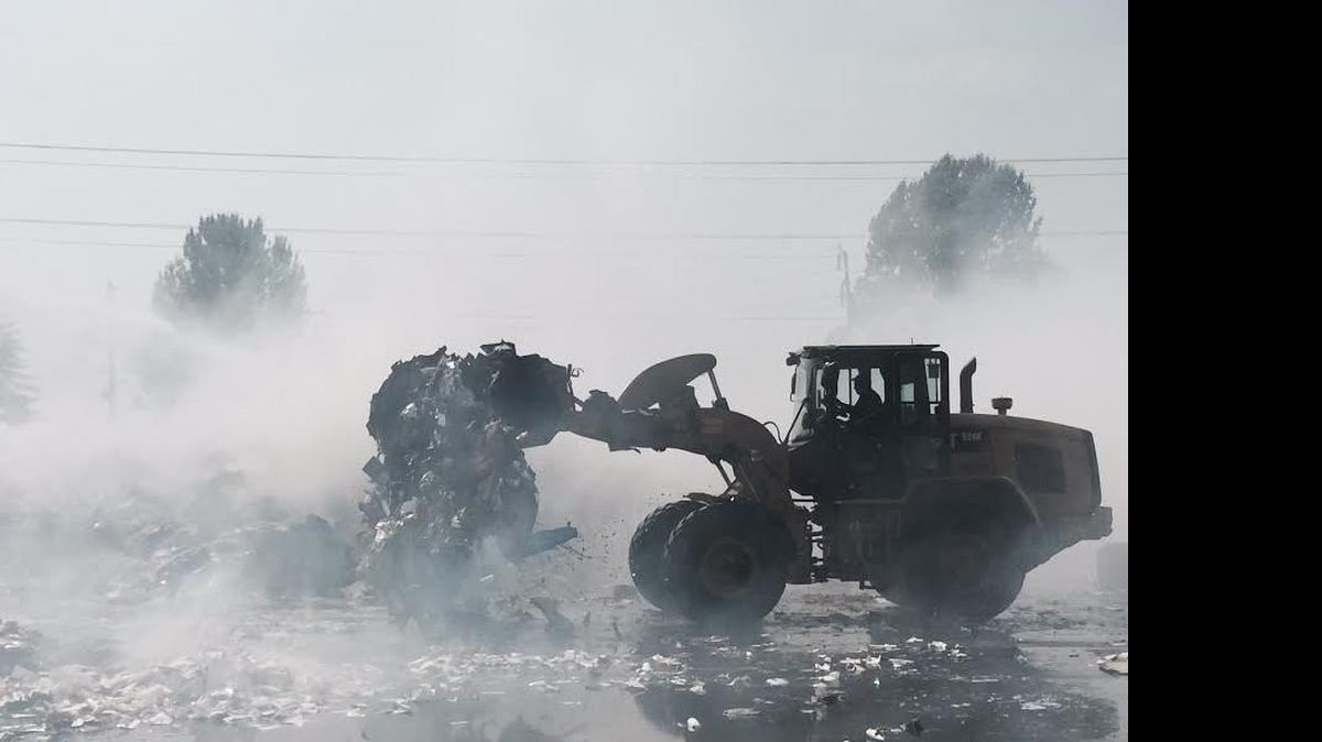 
A front-loader breaks up bundles of paper at a Kent recycling plant so firefighters can easily douse flames.
