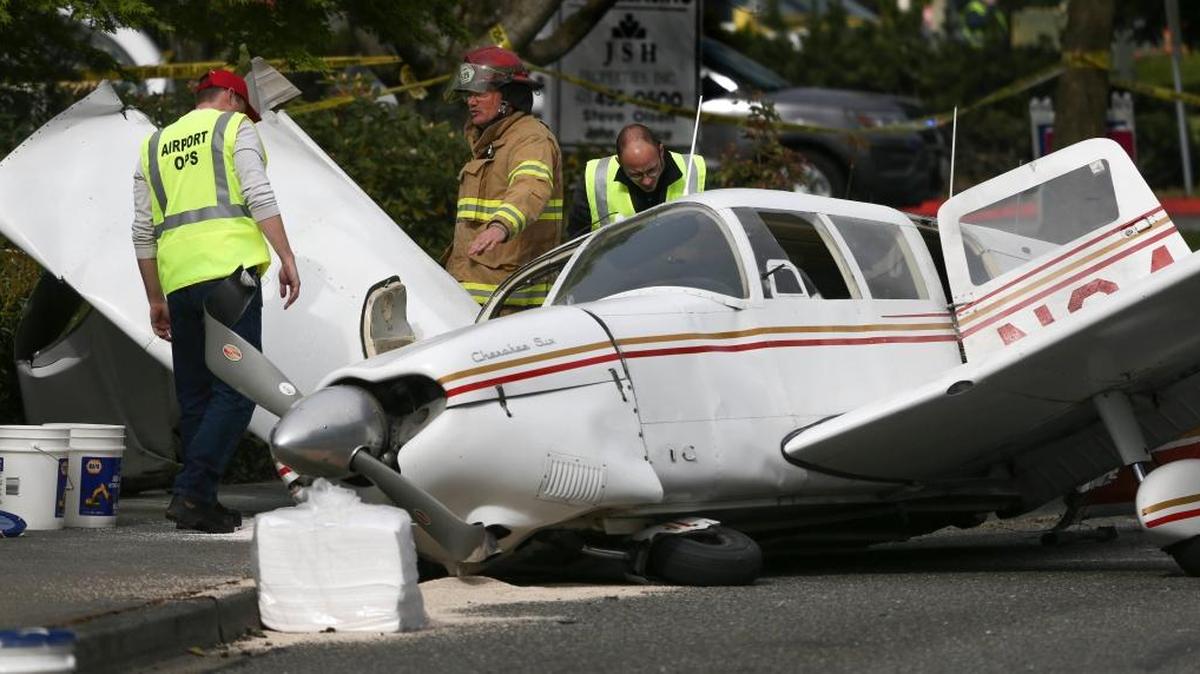 A firefighter and two Snohomosh County Airport workers look over a plane that crashed on Harbor Point Boulevard Southwest and Mukilteo Speedway, after losing power on takeoff from Paine Field on Tuesday, May 2, 2017, in Mukilteo, Wash. Police say there are no injuries but several vehicles were damaged.