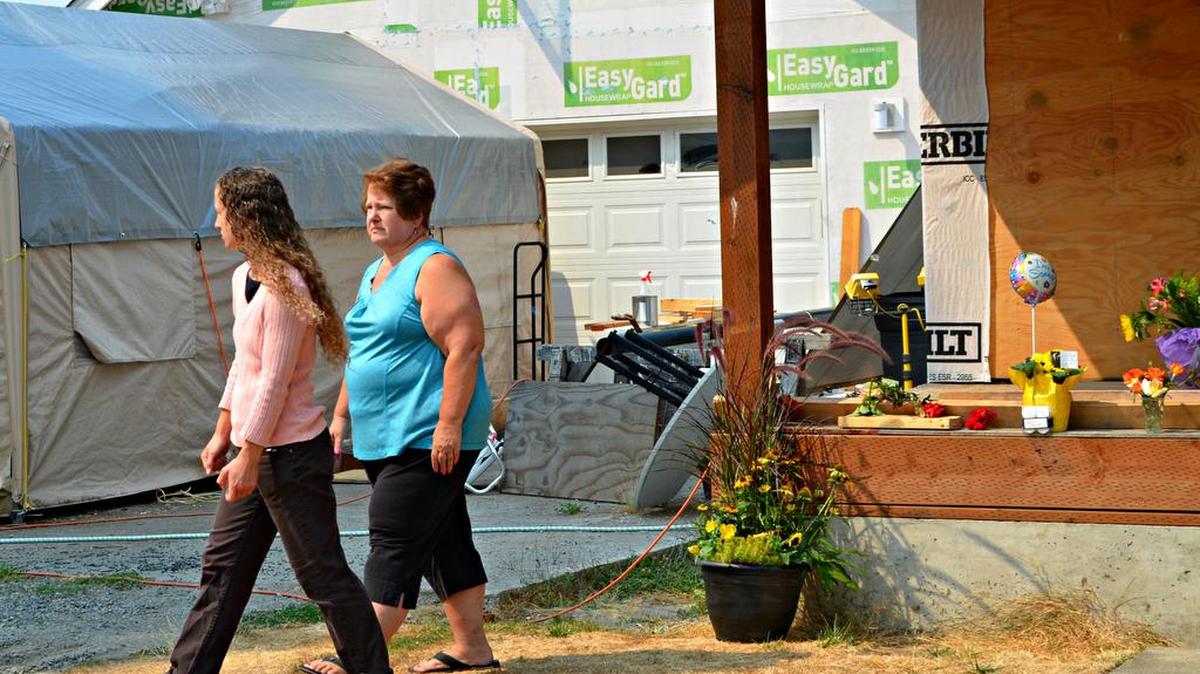 
Dale Andersen, right, and her daughter, Megan Andersen, walk away after leaving a clutch of roses at the place where their neighbor, Richard Johnson, was shot to death in Puyallup on Tuesday. “He was a friend to everyone,” Dale Andersen said of Johnson.
