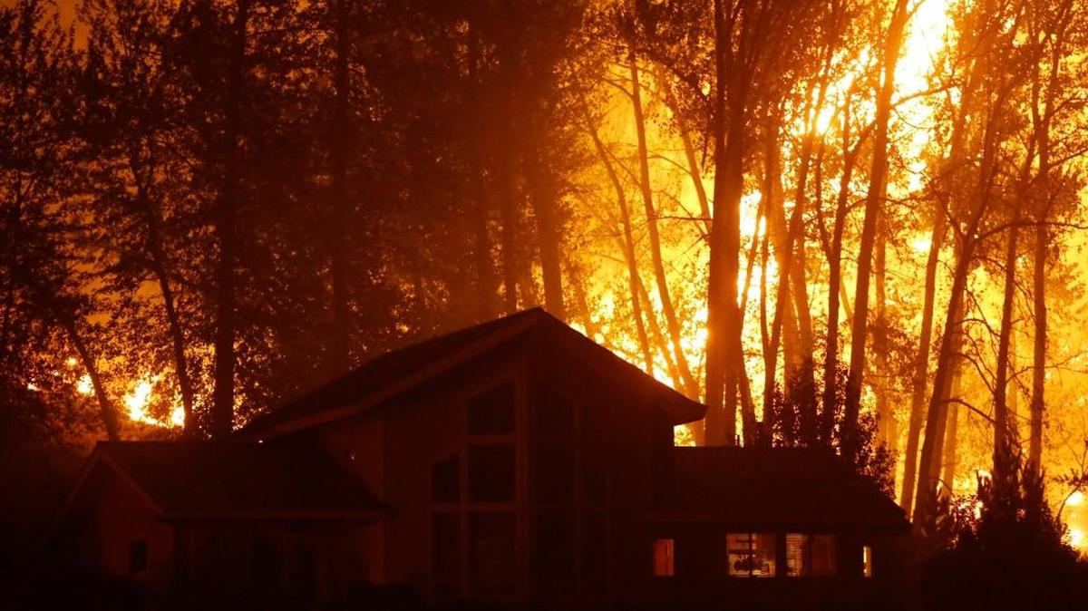 A wildfire burns behind a home on Twisp River Road on Thursday, Aug. 20, 2015, in Twisp. Three firefighters died and one was criticallly injured in the blaze, which eventually consumed 11,000 acres