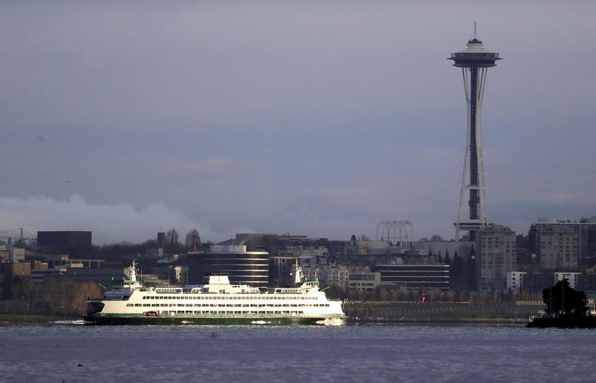 FILE - In this Dec. 27, 2018, file photo, a Washington State ferry heading into Elliott Bay is illuminated by the sun as the city behind remains under clouds in Seattle.. Authorities say a Washington State ferry struck a whale Tuesday night, May 28, 2019, during a sailing from Seattle to Bainbridge Island. (AP Photo/Elaine Thompson,File)