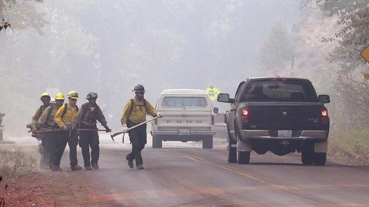 
Firefighters walk through heavy smoke Sunday near Twisp. The Okanogan Complex of wildfires grew to 403 square miles Tuesday while the Chelan Complex now covers 146,375 acres. 

