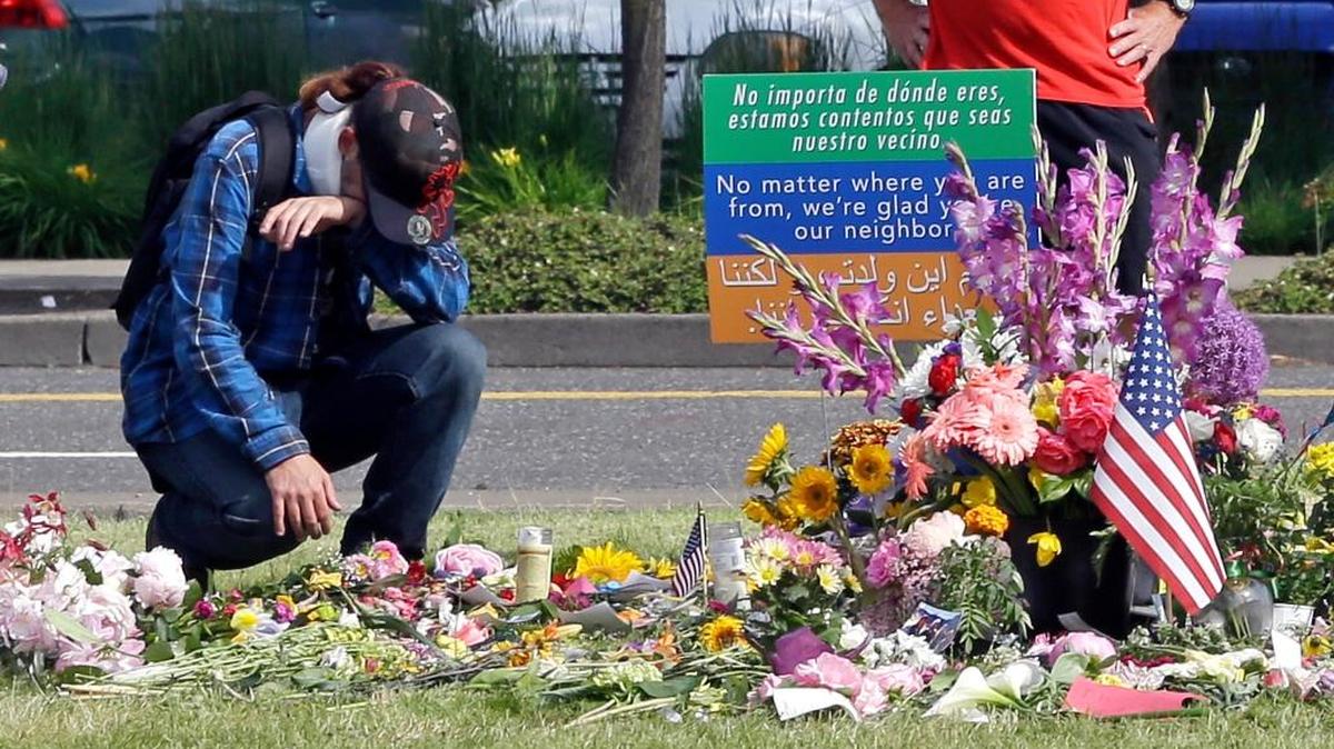 An unidentified man kneels in Portland, Ore., Wednesday, May 31, 2017, at a memorial for two men fatally stabbed on a light rail train in Portland last week. The man charged with fatally stabbing the two men and injuring a third who tried to shield young women from an anti-Muslim tirade, appeared to brag about the attacks as he sat in the back of a police patrol car according to court documents.