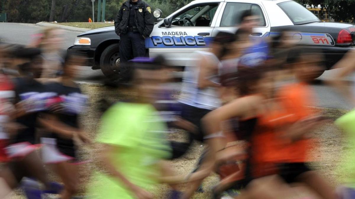 Madera police officer John Rosel, top, watches the Reserve Race pass as he works traffic control along a park street during the CIF Central Section Championships 2013 in Fresno, Calif. Officers often are called upon to provide traffic control for events or can be hired by businesses to do so. They retain their full law enforcement powers during such duties.