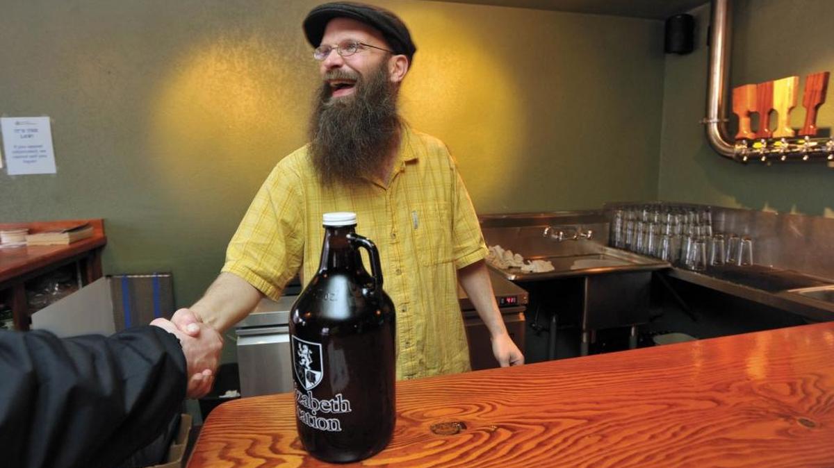 
Jim Parker serves up the first growler of the day on the first full day of operations at Kulshan Brewing Co. on April 3, 2012 in Bellingham. Growlers are considered open containers, so they should be transported in the trunk.
