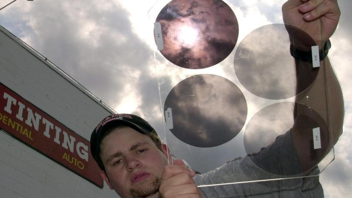 Tom Newsted of Midwest Tinting in Missouri holds a sample of tinted glass applied to cars. The two on the left exceed 24 percent and would be illegal in Washington state. The two on the right, at 5 percent and 20 percent, would be OK.