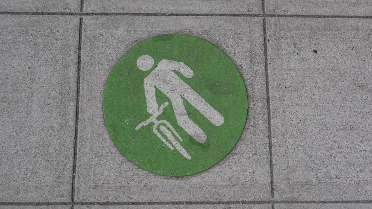 The green sign tries to clarify the message to mean that cyclists are required to walk their bikes on downtown sidewalks.