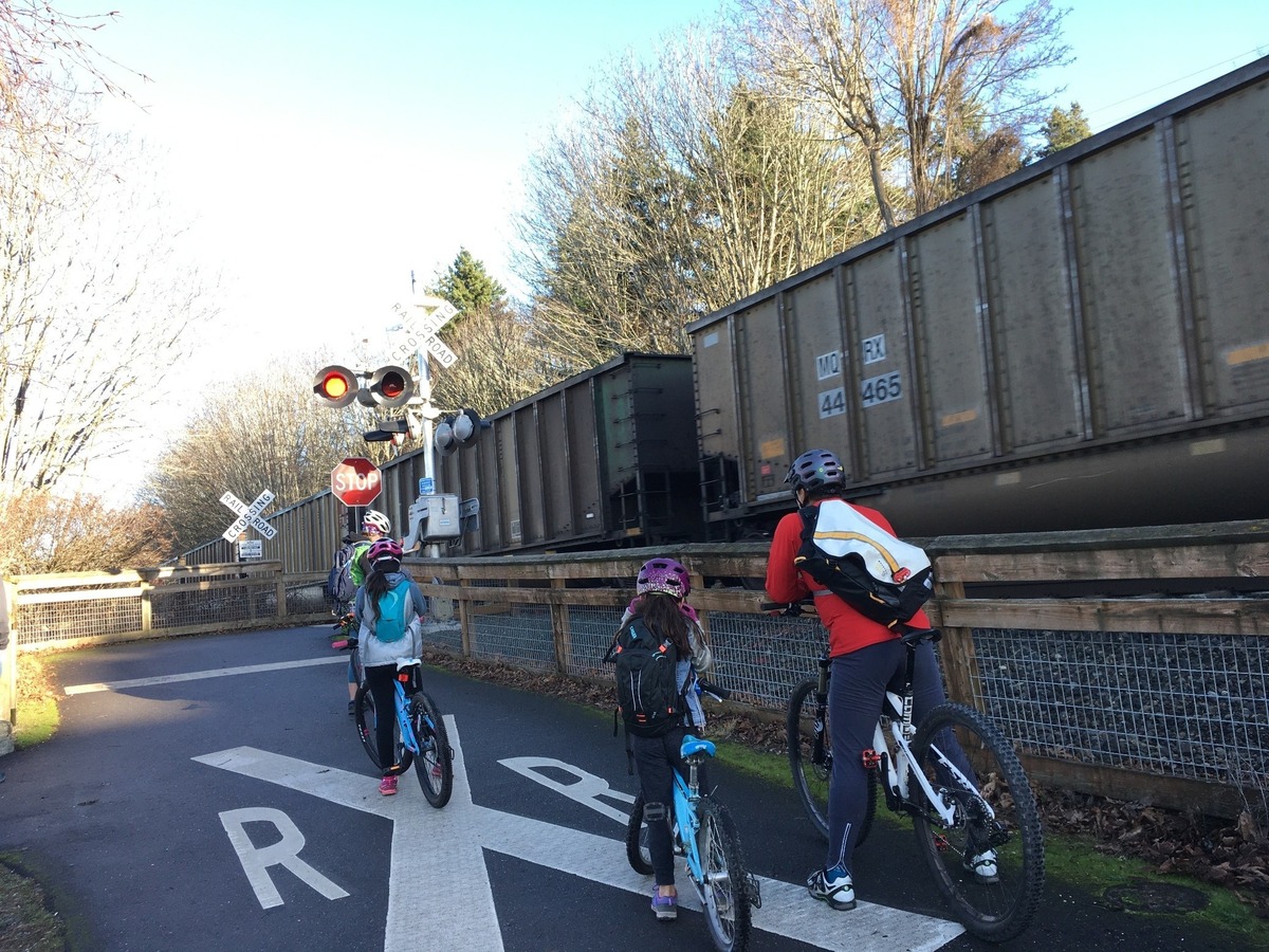 Bicyclists wait for a train at the South Bay Trail crossing on the north end of Boulevard Park on New Year’s Day in 2020. The city is detouring the trail for several days to install a gate at the crossing.