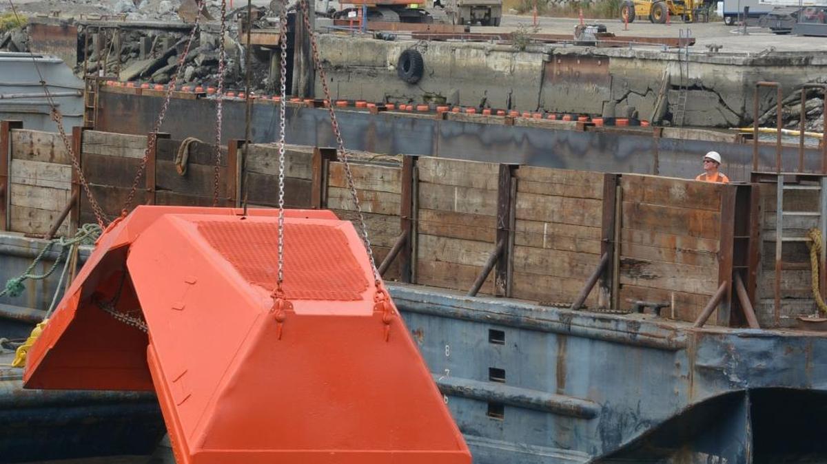 A worker stands near dredging equipment stationed in the middle of Whatcom Waterway in August 2015. Crews will clean up historic contamination in the downtown Bellingham channel this year.