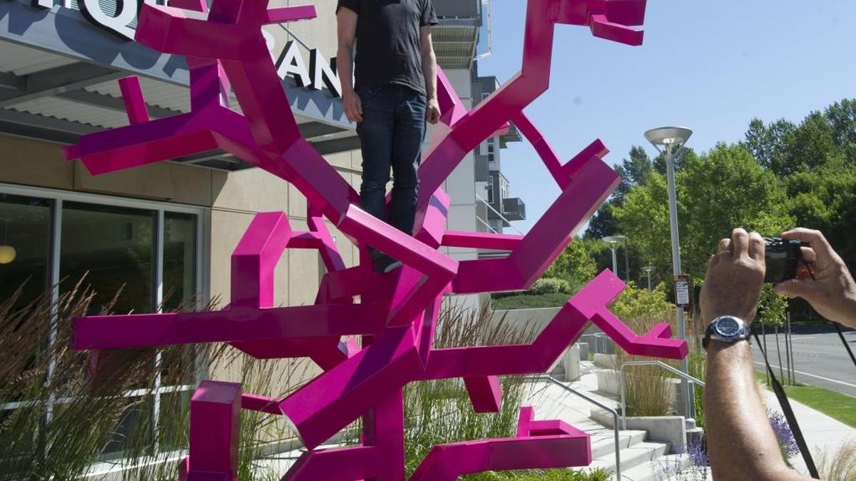 Artist Jacob Dahlgren, stands on his sculpture ‘Constructing a New World,’ while he has photo taken after the piece was installed on the corner of Barkley Boulevard and Newmarket Street in Bellingham, Tuesday, June 23, 2015. The artwork was commissioned by the Barkley Company and the Talbot family.