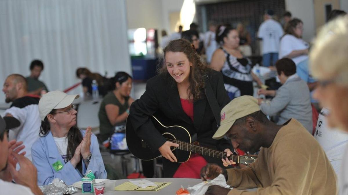 Phina Pipia of the “New Old Time Chautauqua” plays music for visitors at the annual Project Homeless Connect at Bellingham High School in 2013. The event provides services for the homeless and needy.