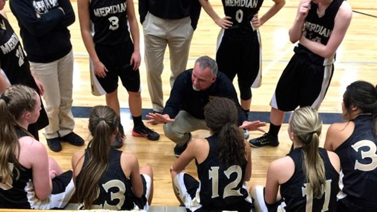 Mark Gilmore, Meridian High School varsity girls basketball coach, talks with his team during a game.