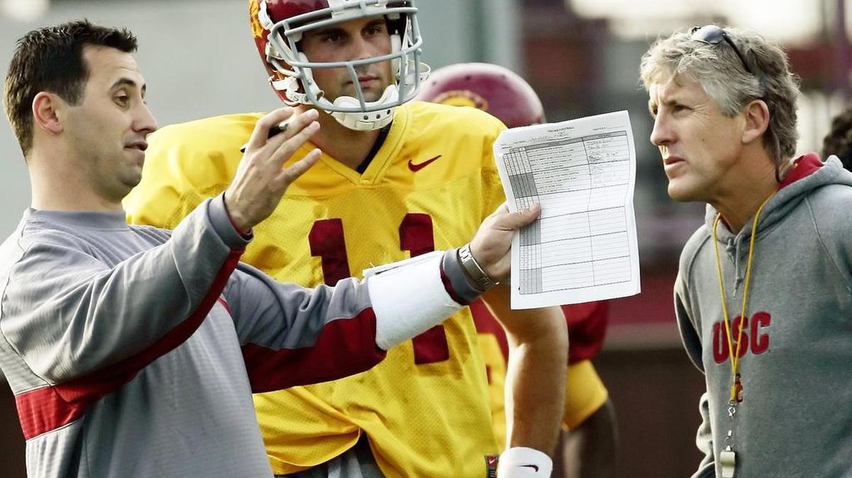 
Former USC coach Pete Carroll, right, talks to then-assistant head coach Steve Sarkisian as quarterback Matt Leinart looks on. Sarkisian was fired by USC as head coach Monday.
