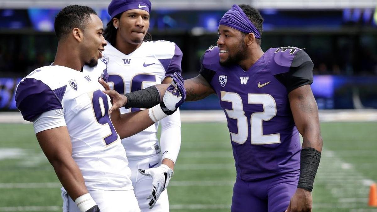 Washington’s Budda Baker (32) pushes Myles Gaskin (9) as Sidney Jones looks on — the trio will have a big say in the Huskies’ season.