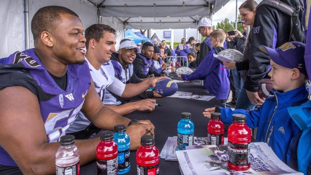 Players sign autographs before the University of Washington Huskies spring football preview at Husky Stadium on Saturday.