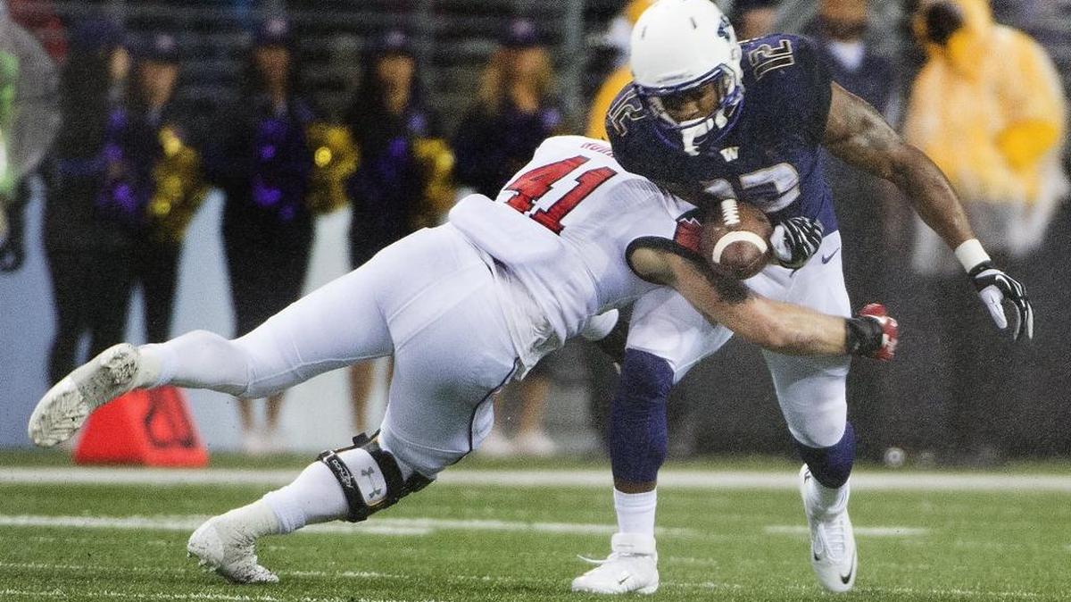 Utah linebacker Jared Norris jars the ball loose from UW running back Dwayne Washington in the second quarter Saturday at Husky Stadium in Seattle. It was one of four turnovers for the Huskies.
