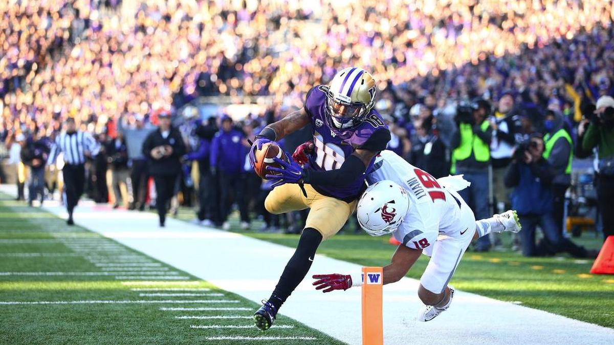 Washington’s Isaiah Renfro, left, makes a leap for the endzone against the defense of Washington State’s Shalom Luani during the first half of the Huskies’ 45-10 win in the 108th Apple Cup in November.
