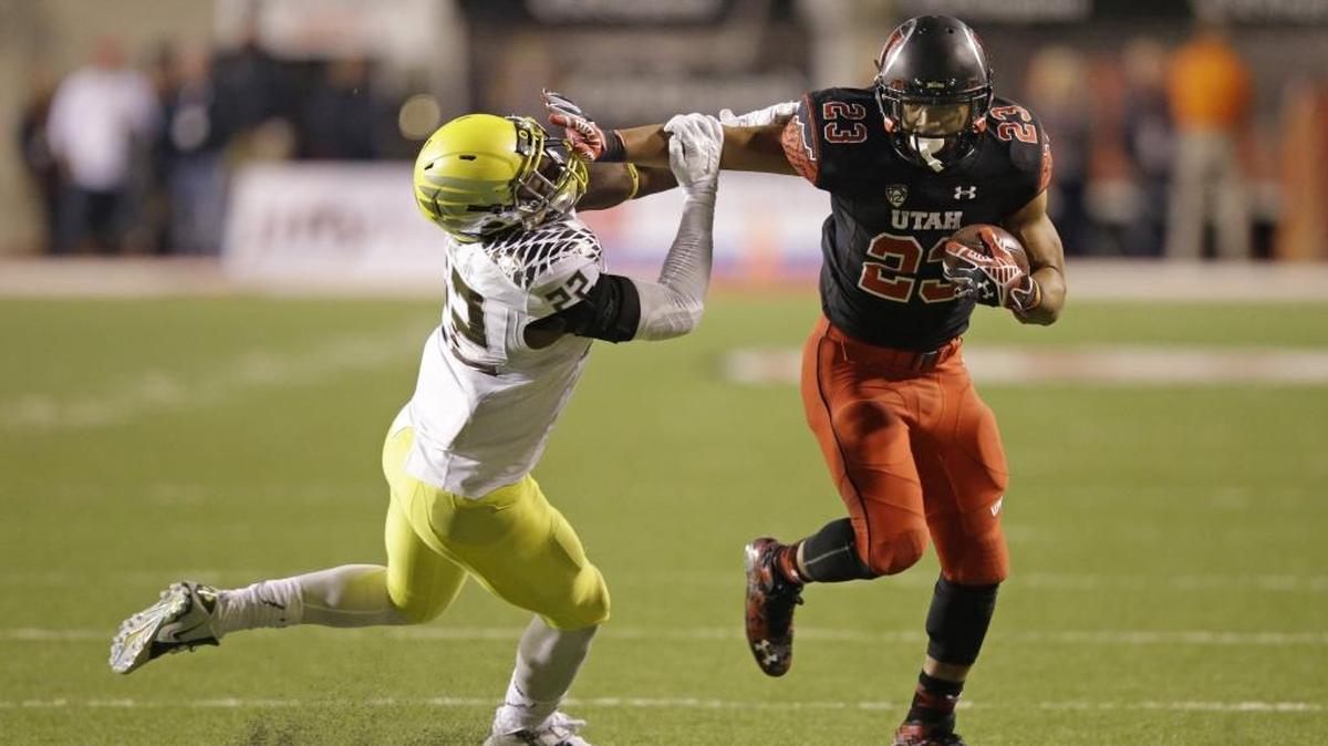 
Oregon linebacker Derrick Malone, left, attempts to make a tackle as Utah running back Devontae Booker carries the ball during an NCAA college football game in Salt Lake City. Booker's 1,512 rushing yards in 2014 were the second most in school history by seven yards. Many expect Booker to be a Heisman candidate in 2015. (AP Photo/Rick Bowmer)
