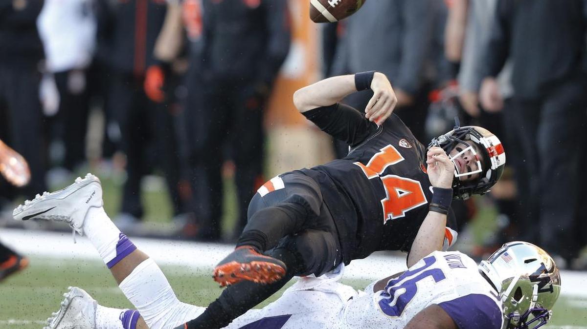Oregon State quarterback Nick Mitchell fumbles the ball after being hit by Washington linebacker Azeem Victor on Saturday in Corvallis, Oregon.