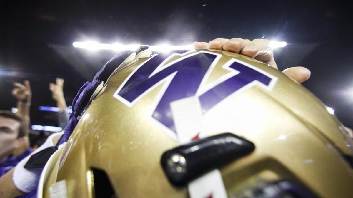 Hands slap a players helmet in celebration after students rushed the field following Washington’s 44-6 win against Stanford. The Washington Huskies played the Stanford Cardinal in a football game at Husky Stadium in Seattle, Wash., on Friday, September 30, 2016.