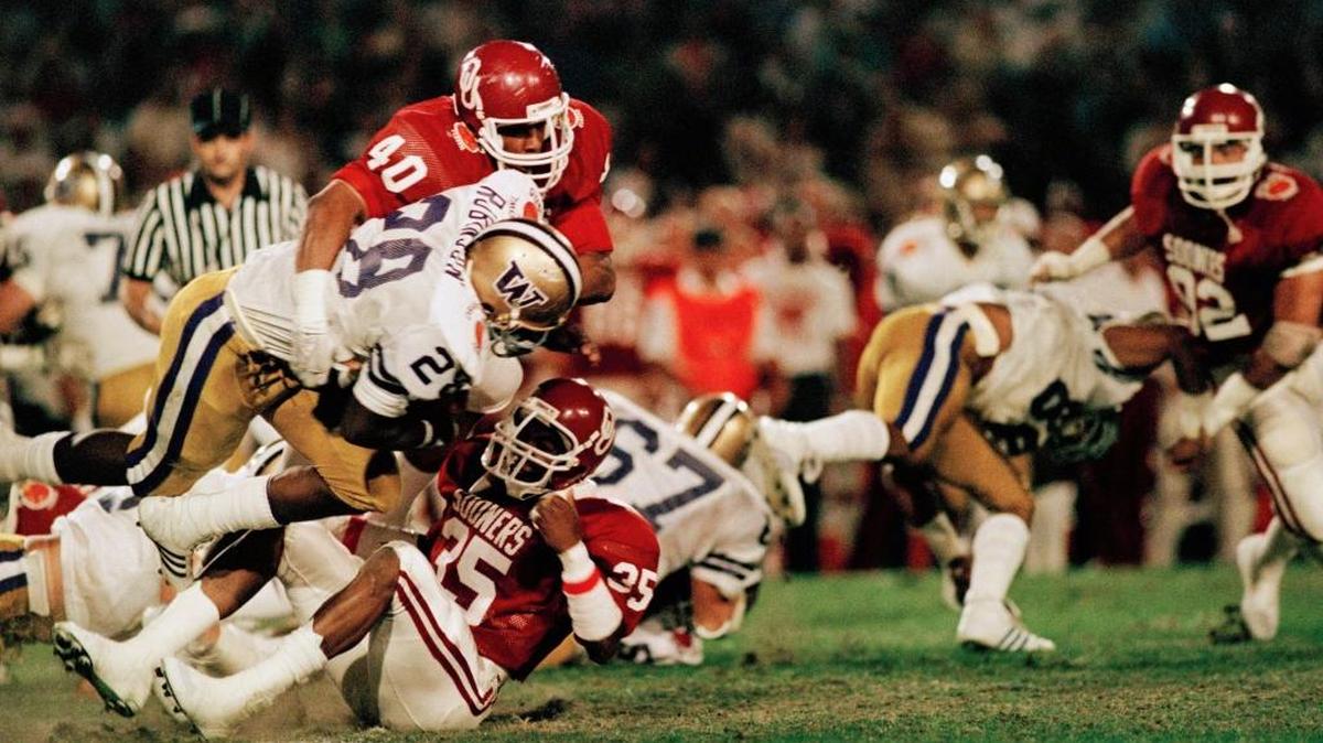 Washington’s Jacque Robinson (28) falls forward over Oklahoma’s Tony Rayburn (35) as he is pushed to the ground by Darrell Reed (40) in the first quarter action Tuesday, Jan. 1, 1985 in the Orange Bowl in Miami.