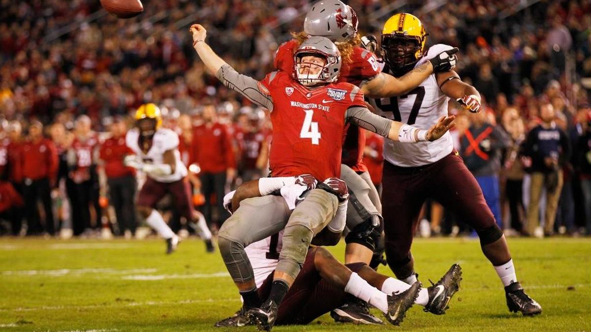 Washington State’s Luke Falk has to throw the ball away as he is hit by Minnesota’s Jonathan Celestin in the fourth quarter of the Holiday Bowl in San Diego on Dec. 27, 2016. The Cougars will get another shot at the Holiday Bowl, this time against Michigan State on Dec. 28 in San Diego.