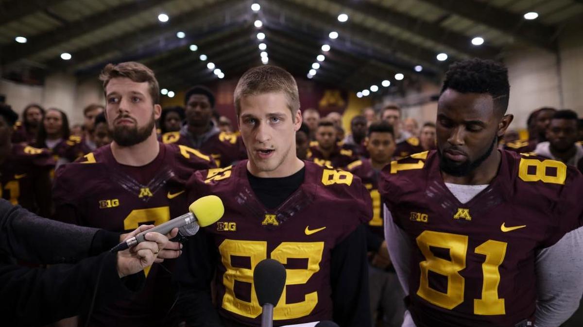 University of Minnesota wide receiver Drew Wolitarsky, center, flanked by quarterback Mitch Leidner, left, and tight end Duke Anyanwu, with the rest of the team standing behind them, read a statement on behalf of the players on Thursday, Dec. 15, 2016. Players said they would not participate in any football activities until a resolution could be found regarding the suspension of 10 of their teammates.