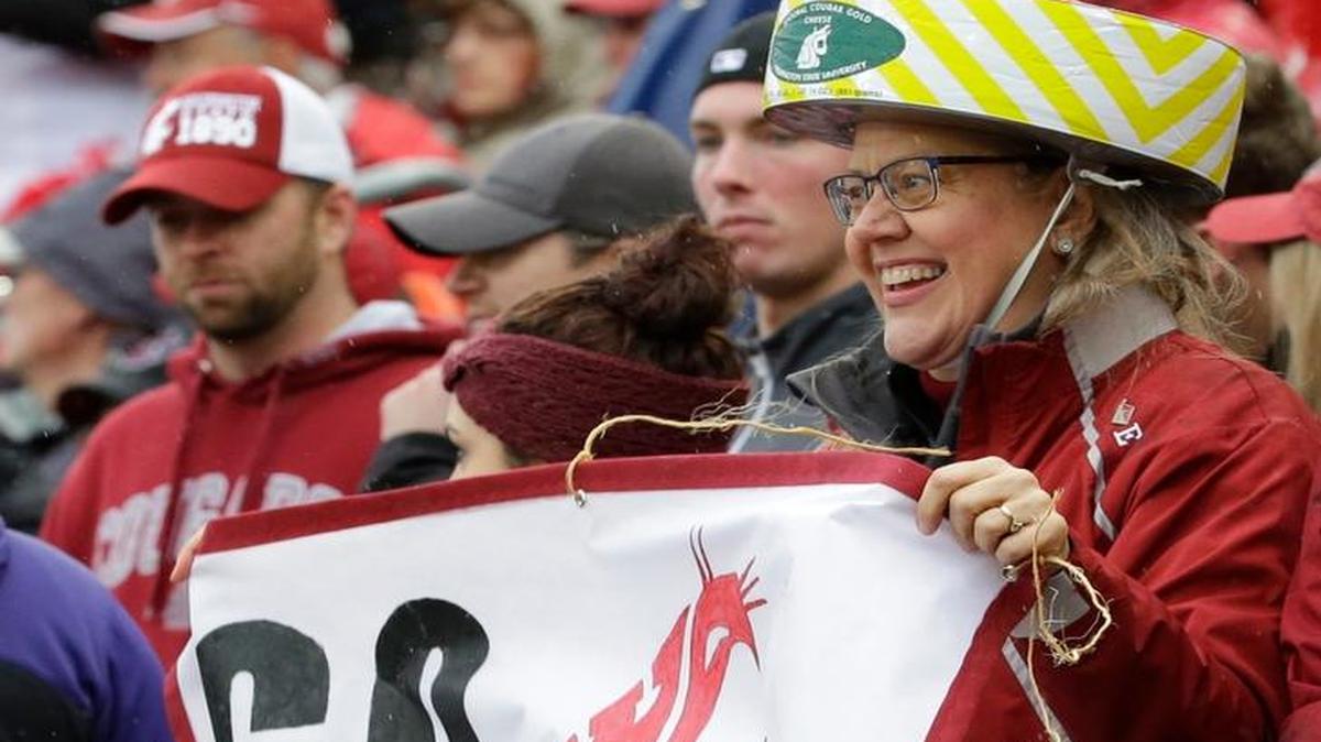 A Washington State fan wears a hat during an NCAA college football game against Washington that is modeled after the distinctive canned Cougar Gold cheese produced at the university, Friday, Nov. 25, 2016, in Pullman, Wash.
