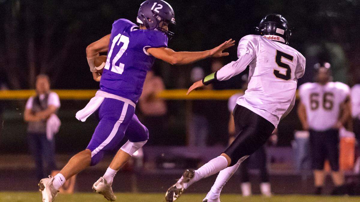 Nooksack Valley quarterback Joseph Brown (12) stiff arms Meridian defender Jaeger Fyfe (5) as he runs for a touchdown early in the second quarter on Friday evening Sept. 30, at Nooksack Valley High School in Everson.