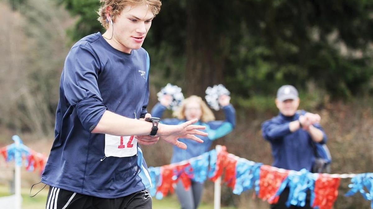 
Lynden Christian 16-year-old, Josh Lingbloom, checks his watch for a final time as he crosses the finish line placing second in the 2014 Birch Bay Marathon.
