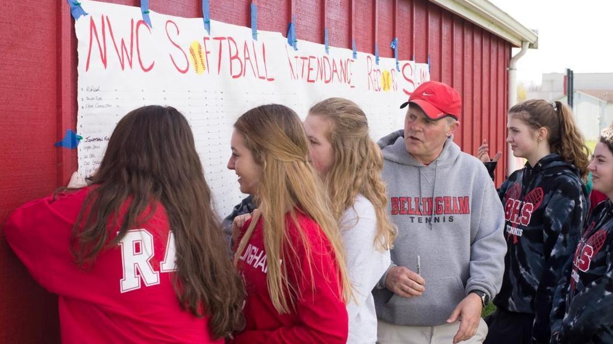 Students from Bellingham High School sign an attendance sheet attached to the back of a dugout before a softball game between Meridian and Bellingham on Tuesday, March 22, in Bellingham.