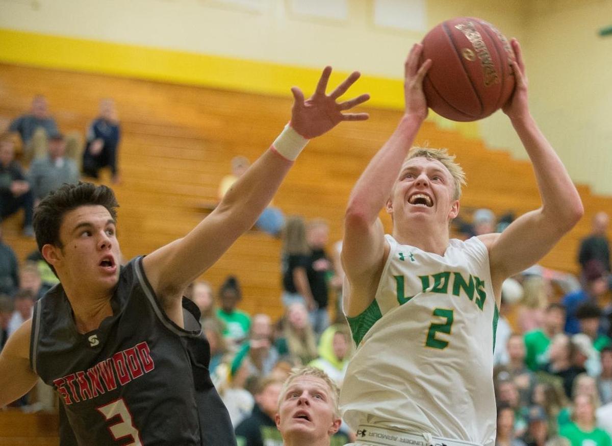 Lynden’s Kobe Elsner, right, shoots and scores around the defense of Stanwood’s Matt Vail, left, on Tuesday, Nov. 28, at Lynden High School.