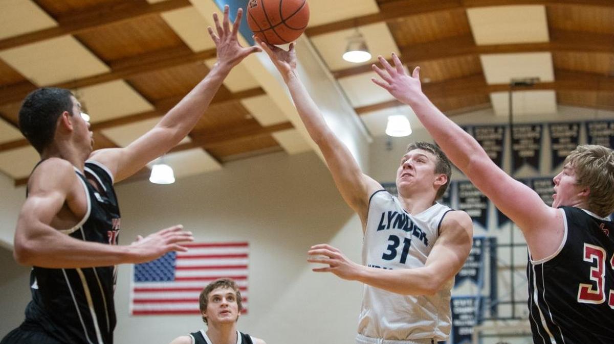 Lynden Christian’s Zach Roetcisoender takes a shot between the arms of Mount Baker’s Timothy Soares and TJ Bass on Friday, Feb. 5, at Lynden Christian High School.