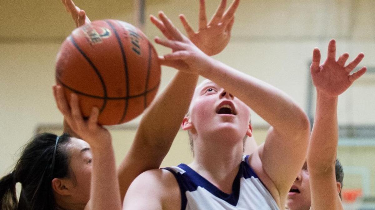 Nooksack Valley's Katrina Gimmaka goes between Forest Ridge's Portia Plackson, right and Cindy Hsu, left, to take a shot on Wednesday, Feb. 17, in Everson.
