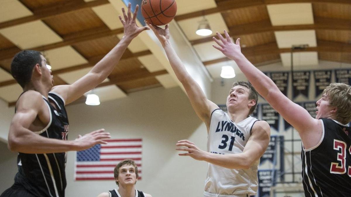 Lynden Christian’s Zach Roetcisoender takes a shot between the arms of Mount Baker’s Timothy Soares and TJ Bass Feb. 5 at Lynden Christian.