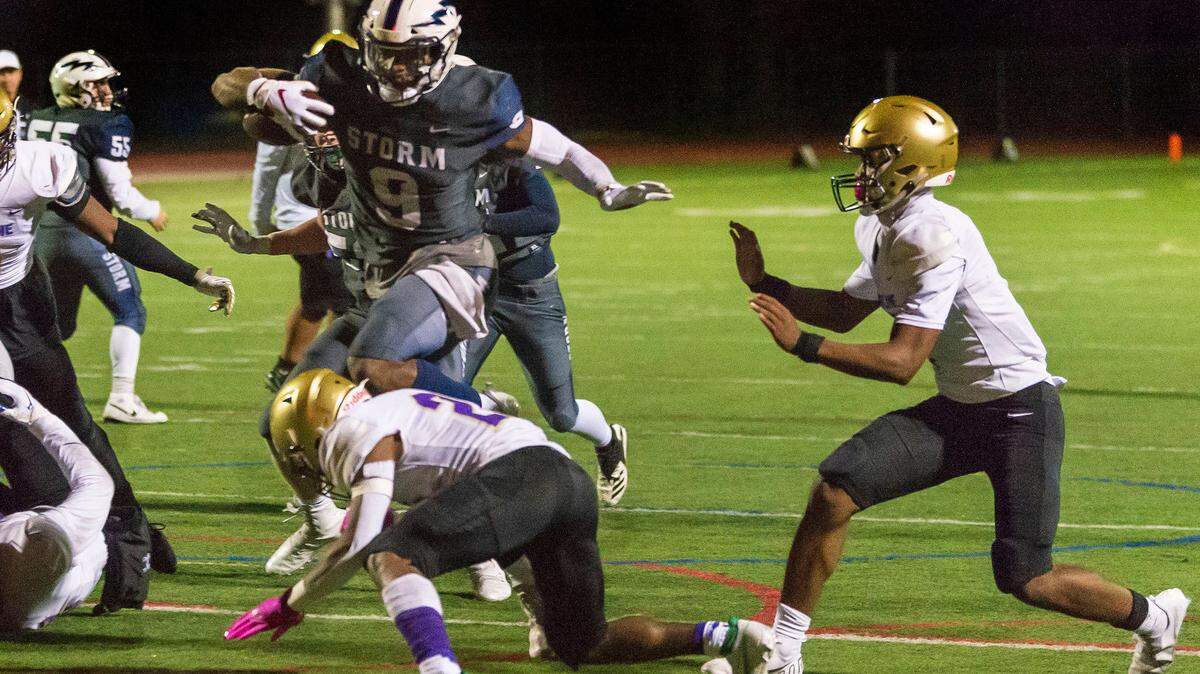 Squalicum running back Djouvensky Schlenbaker (9) hops over Highline defensive back Marcus McCraney (22) for a touchdown during the second quarter on Friday evening Nov. 12, 2021, at Civic Field in Bellingham. Squalicum defeated Highland 49 to 14 to advance to the next round of the division 2A conference playoffs.