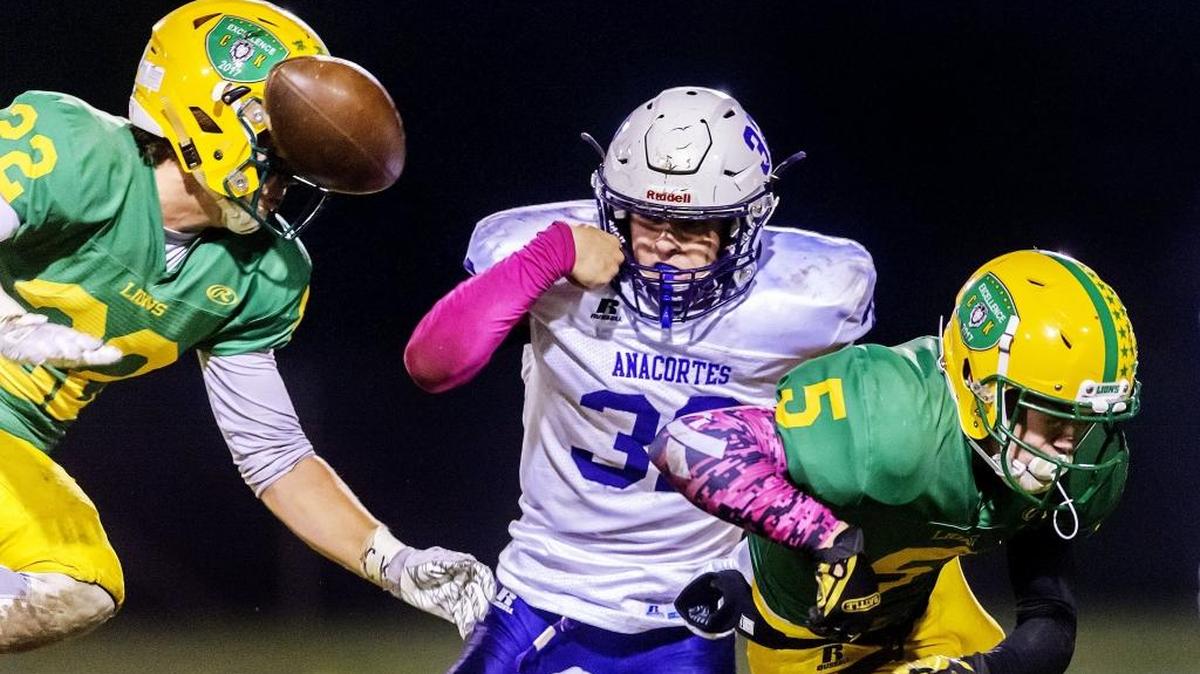 Lynden defensive back Bo Bovenkamp, right causes Anacortes running back Peyton Beaner to fumble as Lynden linebacker Gage Bates moves in for the tackle during an Oct. 13 game. The Lions travel to Tumwater for the first round of the Class 2A state playoffs Friday.