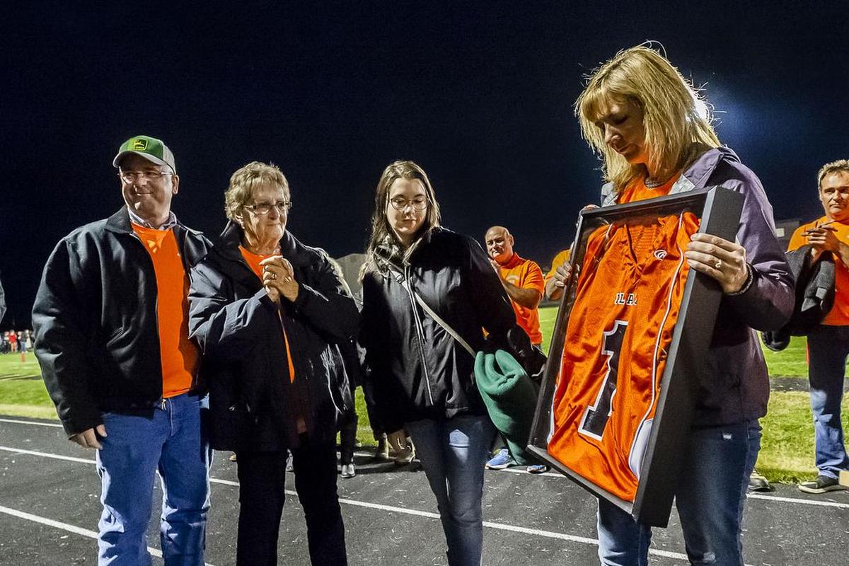 The family of Hall of Fame coach Curt Kramme — from left, his brother Pat Kramme, his mother Gayle Kramme, his daughter Zoe Kramme and his wife Wendy Kramme — look down at his retired jersey during a special halftime celebration on Friday evening, Sept. 14, 2018, at Blaine High School in Blaine, Wash. The 1978 Blaine state championship team was honored and the jersey of team quarterback Curt Kramme was retired. Kramme was also a Hall of Fame coach for the Lynden Lions.