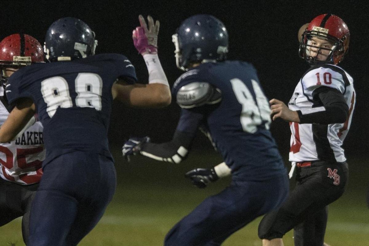 Mount Baker’s Mason Bass looks downfield to throw the ball as Lynden Christian’s defenders close in a 2014 game.