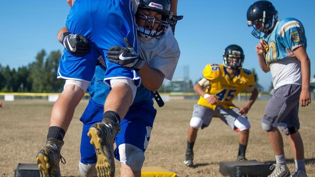 Meridian’s Manny Sabalza, center, picks up a teammate during a tackling drill at practice Aug. 22.