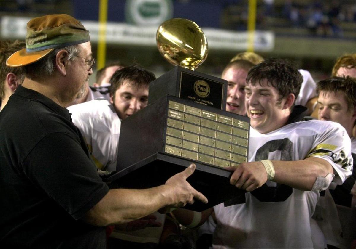 Meridian football coach Bob Ames and running back/linebacker Brady Emmons hold up the Class 2A state championship trophy after the Trojans beat Pullman in 2003 at the Tacoma Dome.