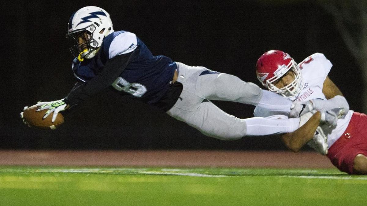 Squalicum’s Damek Mitchell dives toward the end zone with Marysville-Pilchuck’s Keith Pablo hanging from his legs to score a touchdown on Friday, Sept. 16, at Civic Stadium in Bellingham.