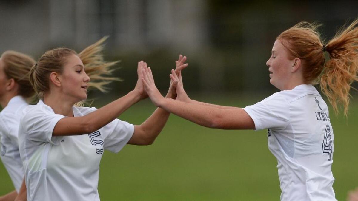 Lynden Christian’s Bailee Den Bleyker, right, receives congratulations from Emily Roetcisoender after one of her two goals vs. Cedar Park Christian.