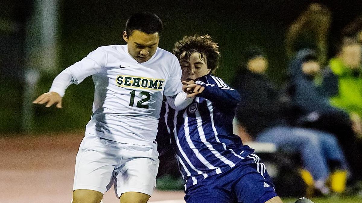 Squalicum defender Bailey Wilson (1), right, prepares to tackle Sehome's Kevin Sun (12) as he approaches the goal during the first half Monday, March 28, at Civic Stadium in Bellingham.