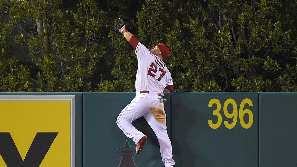 
Mike Trout of the Angels makes an over-the-fence catch on a ball hit by the Mariners’ Jesus Montero during the fourth inning Saturday in Anaheim, Calif. The catch turned what would have been a three-run homer into a harmless out.
