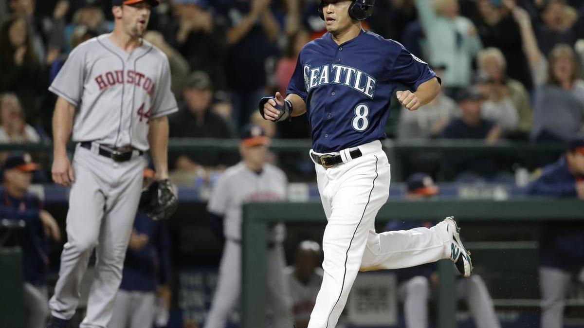 The Mariners’ Norichika Aoki scores as Astros reliever Luke Gregerson walks behind him during Saturday night’s game in Seattle.